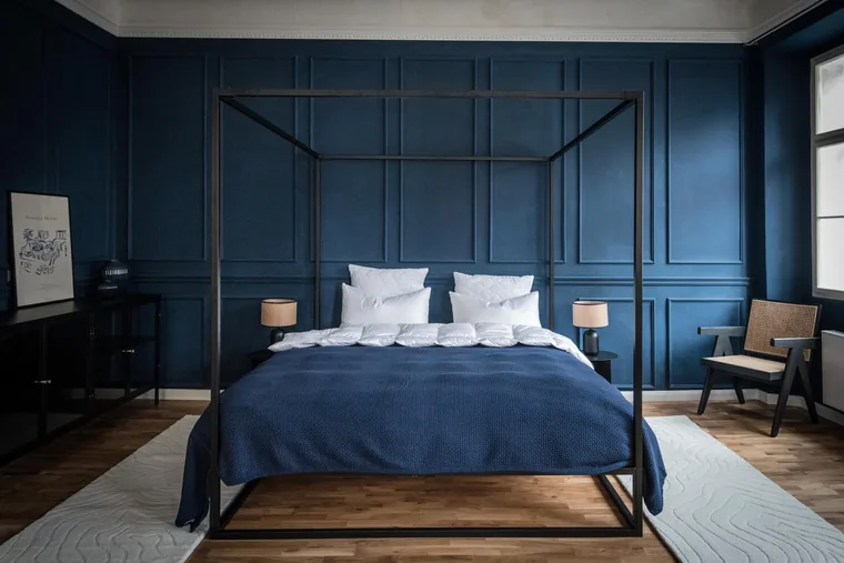 Deep-blue bedroom with a black four-poster bed